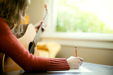 stock photo of a girl writing songs on an acoustic guitar