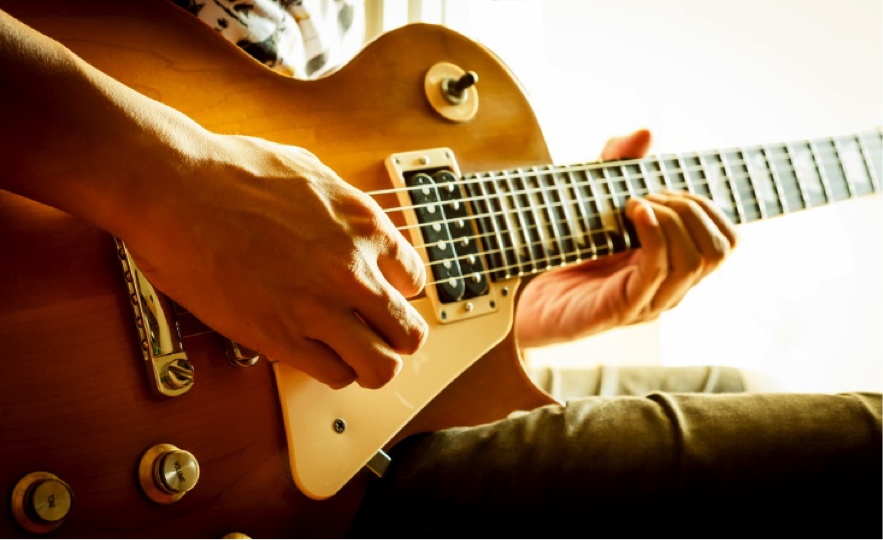 a stock photo showing someone playing a golden Les Paul guitar