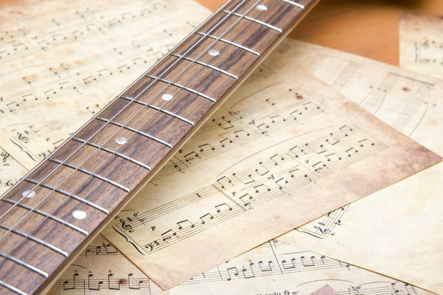 Image of a guitar neck with sheets of music notation