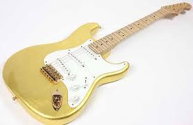 Golden guitar body, hardware and matching headstock. Maple neck, white pick guard, knobs and single coils
