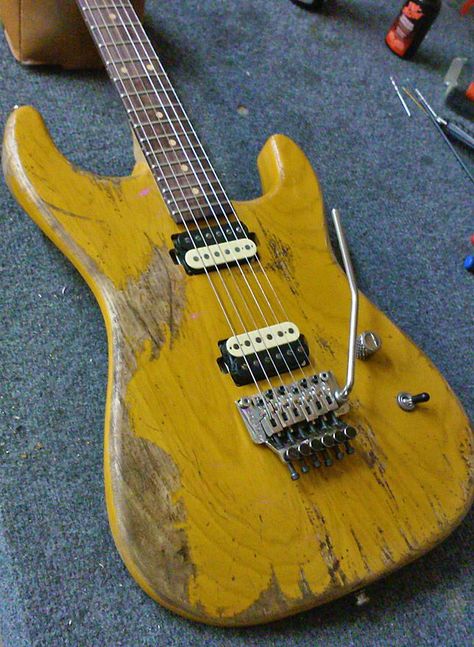 Worn down stained yellow Strat style guitar with Floyd Rose. It has zebra cream-black humbuckers. 