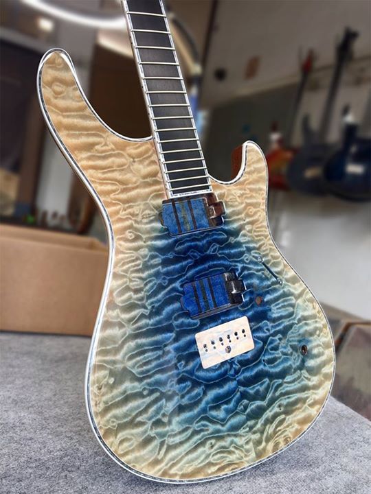 A guitar with a blue to natural wood finish on a quilted maple top.