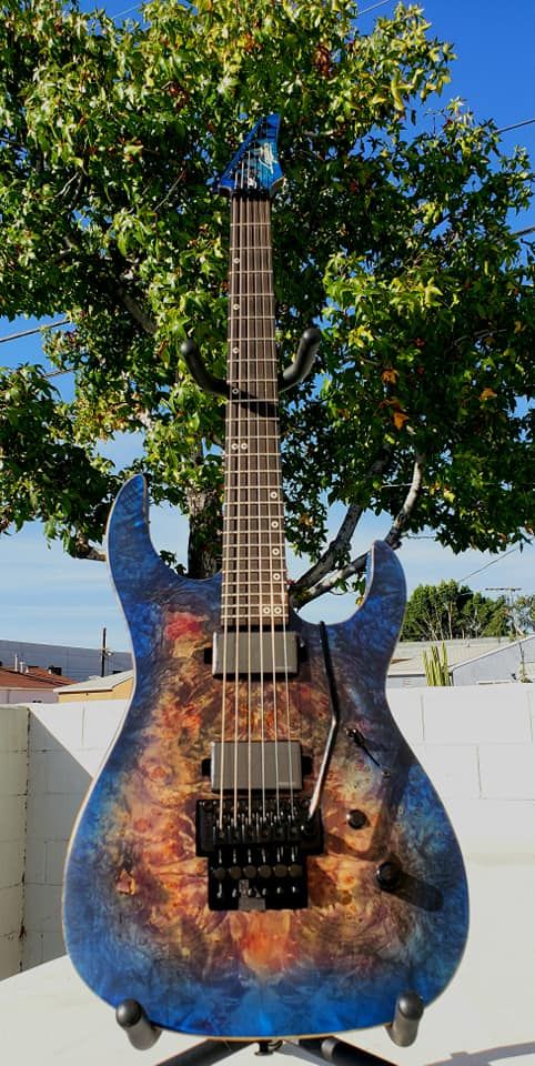A guitar with wild Burl patterns, under a transparent blue-to-red burst