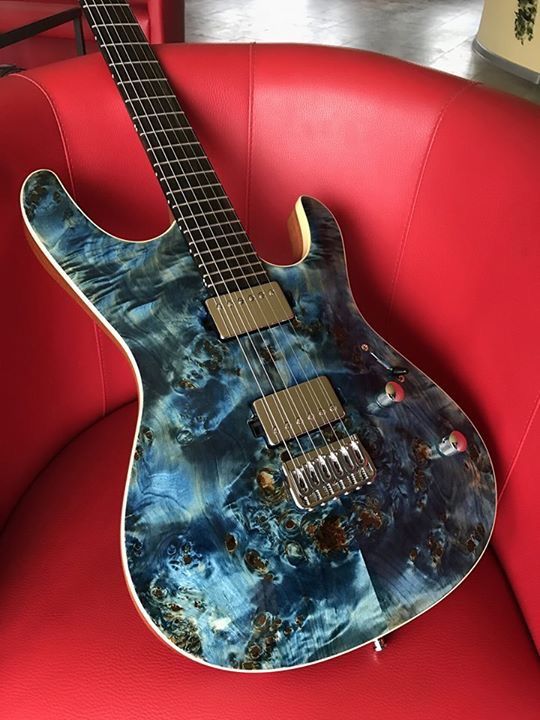 A Mayones guitar in metallic tranparent blue finish with amazing burl wood patterns underneath the finish