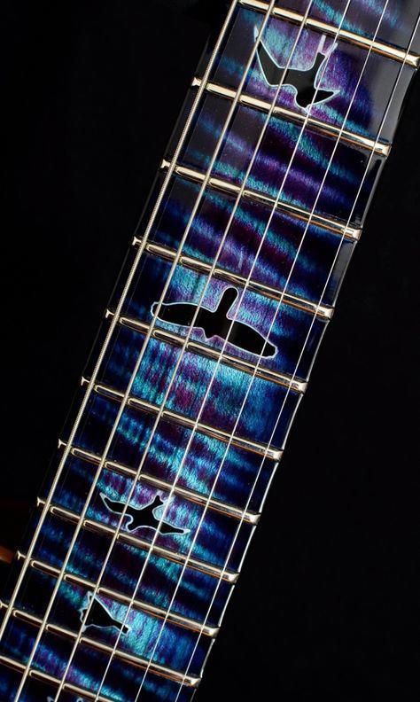 A guitar fretboard treated with a lovely sparkly, blue-teal-colored shading and black birds as fret markers