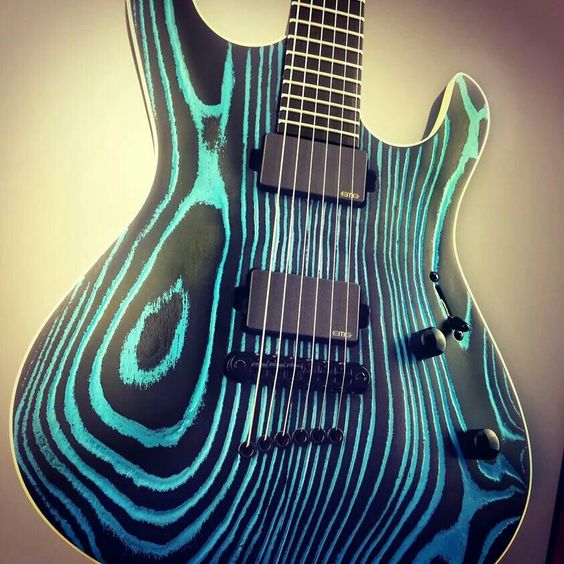 Black guitar with turquoise-colored wood grains. How do you make the paint and wood converge this way?