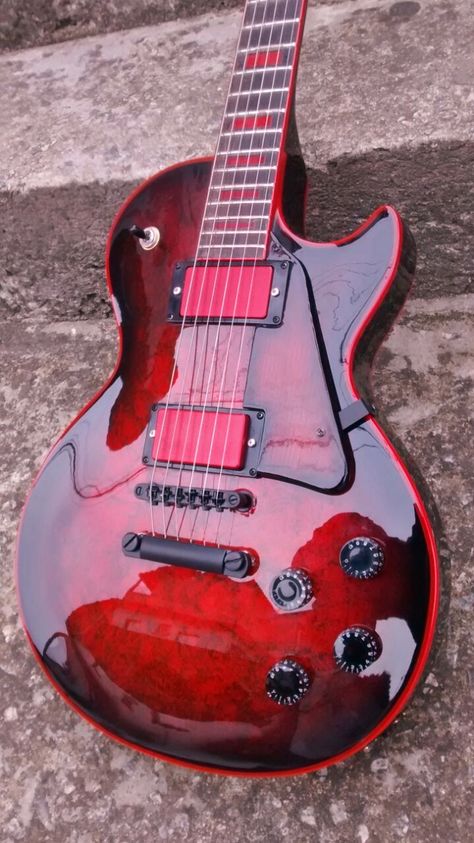 All red Les Paul with red pick up covers, black burst edges and black hardware and knobs