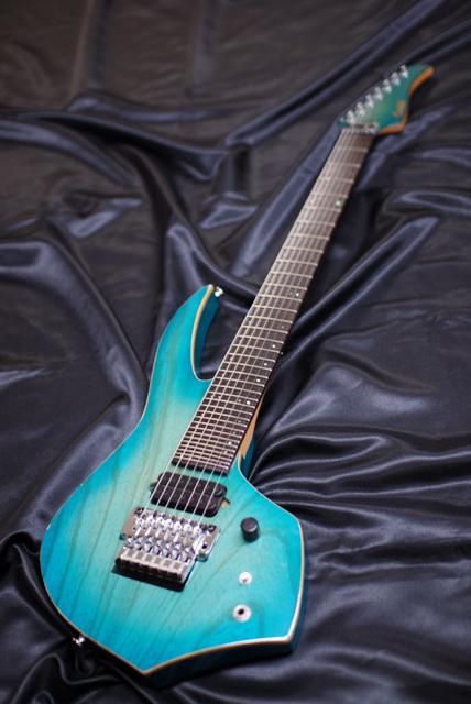 A light blue bleach burst Ibanez guitar with 30 frets. 