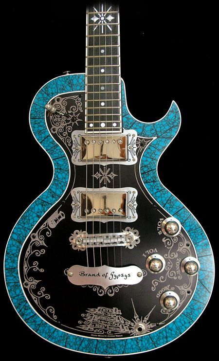 Ornate, rich, busy ornamention on a black body with broad, wide blue binding along the guitar body's edge. 